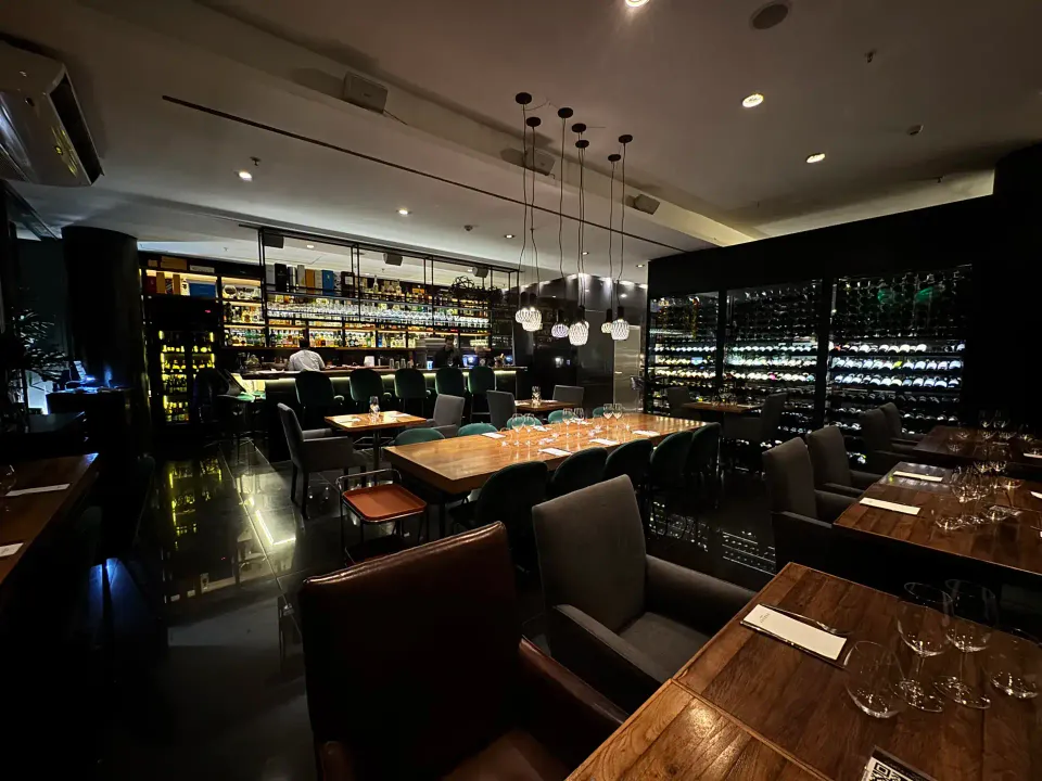 Salón de Verdot Wine Bar con una mesa tendida, copas y la cava al fondo
